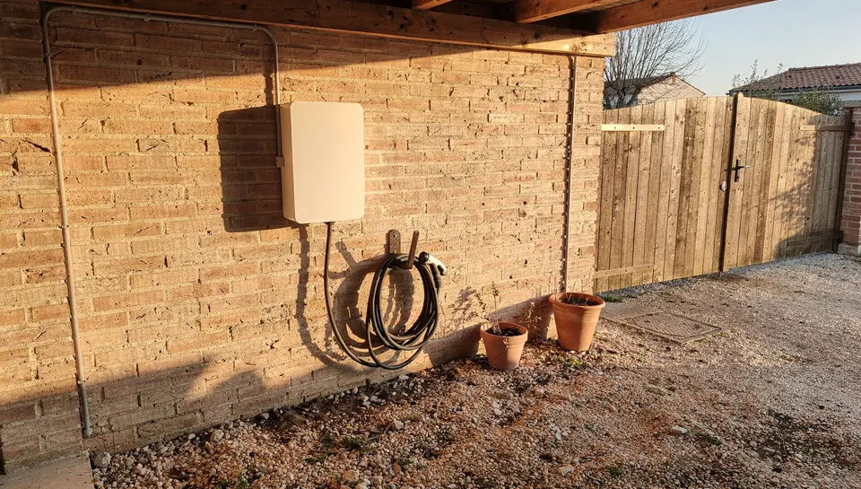 Borne de recharge murale sous un abri voiture, contre un mur de briques